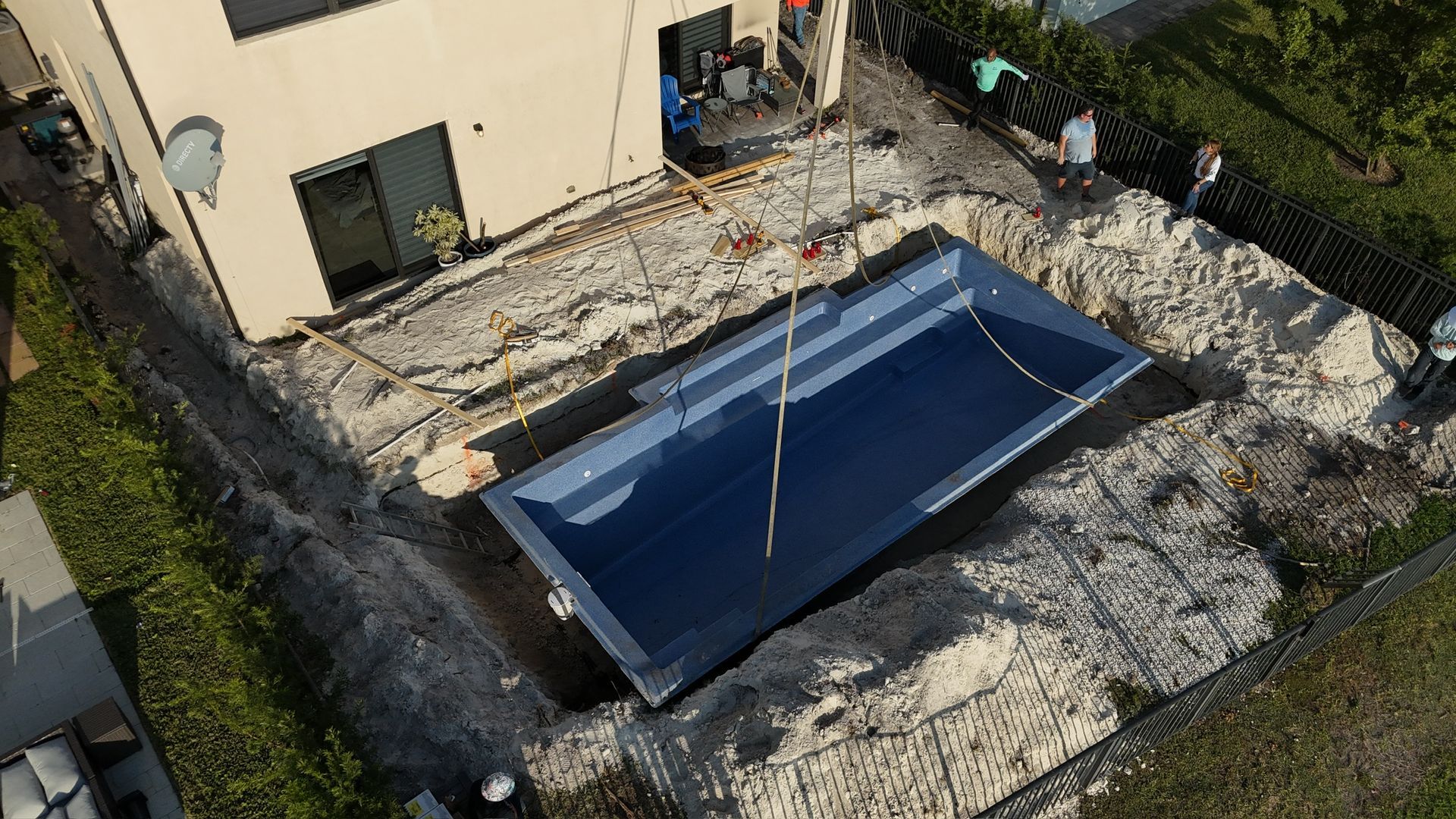 An aerial view of a swimming pool being built in front of a house.