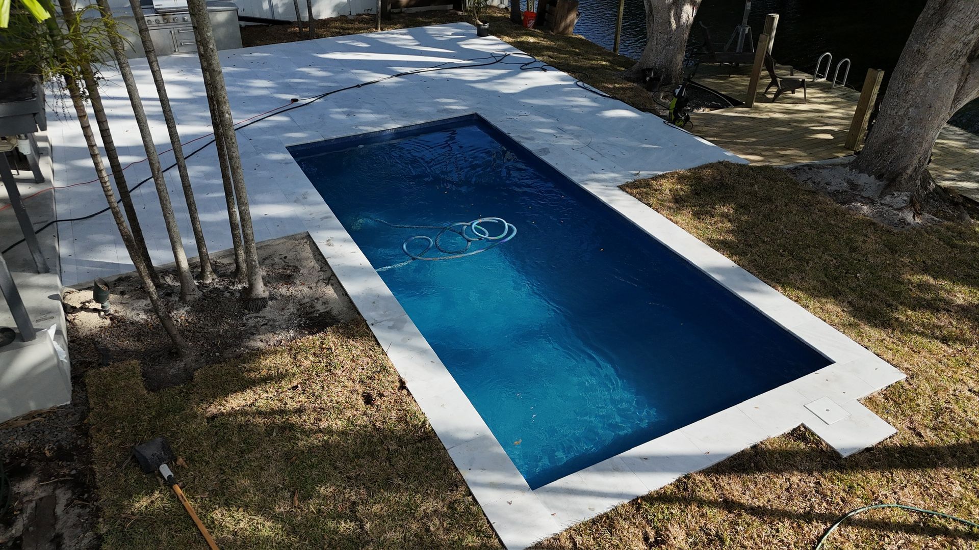 A swimming pool is sitting in the middle of a lush green yard.