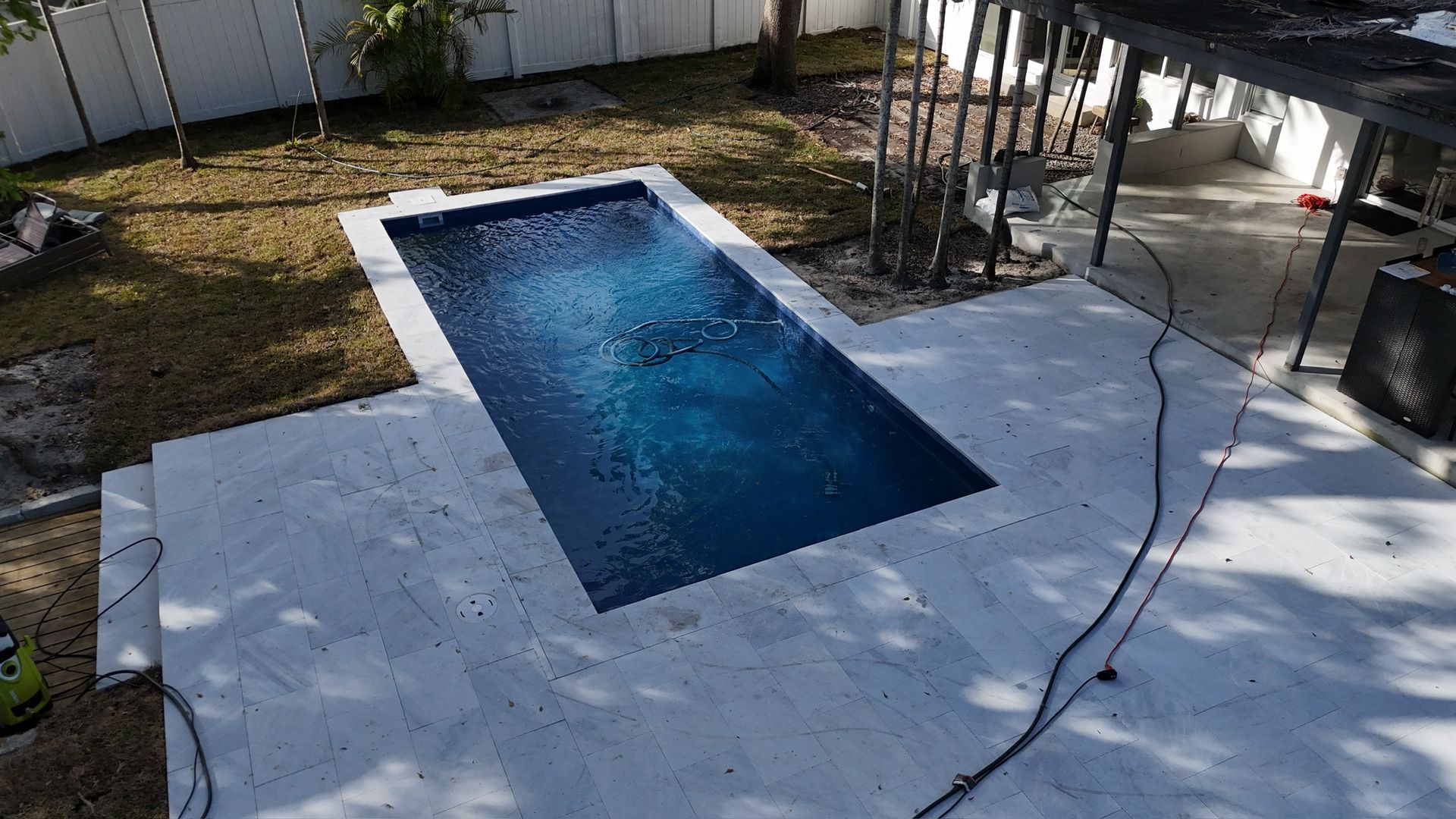 A small swimming pool is sitting on top of a concrete patio in a backyard.