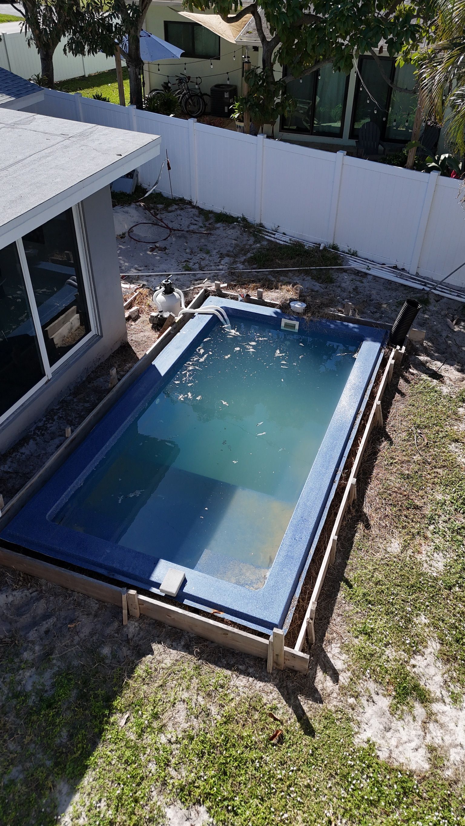 A swimming pool is being built in the backyard of a house.