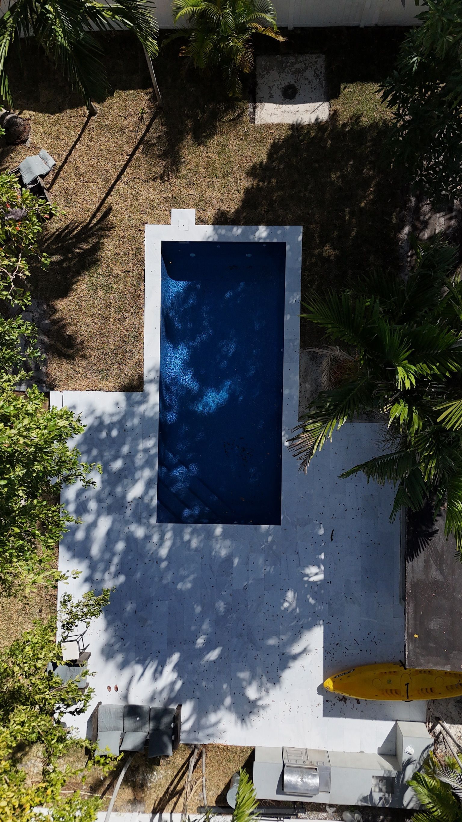 An aerial view of a large swimming pool surrounded by trees.