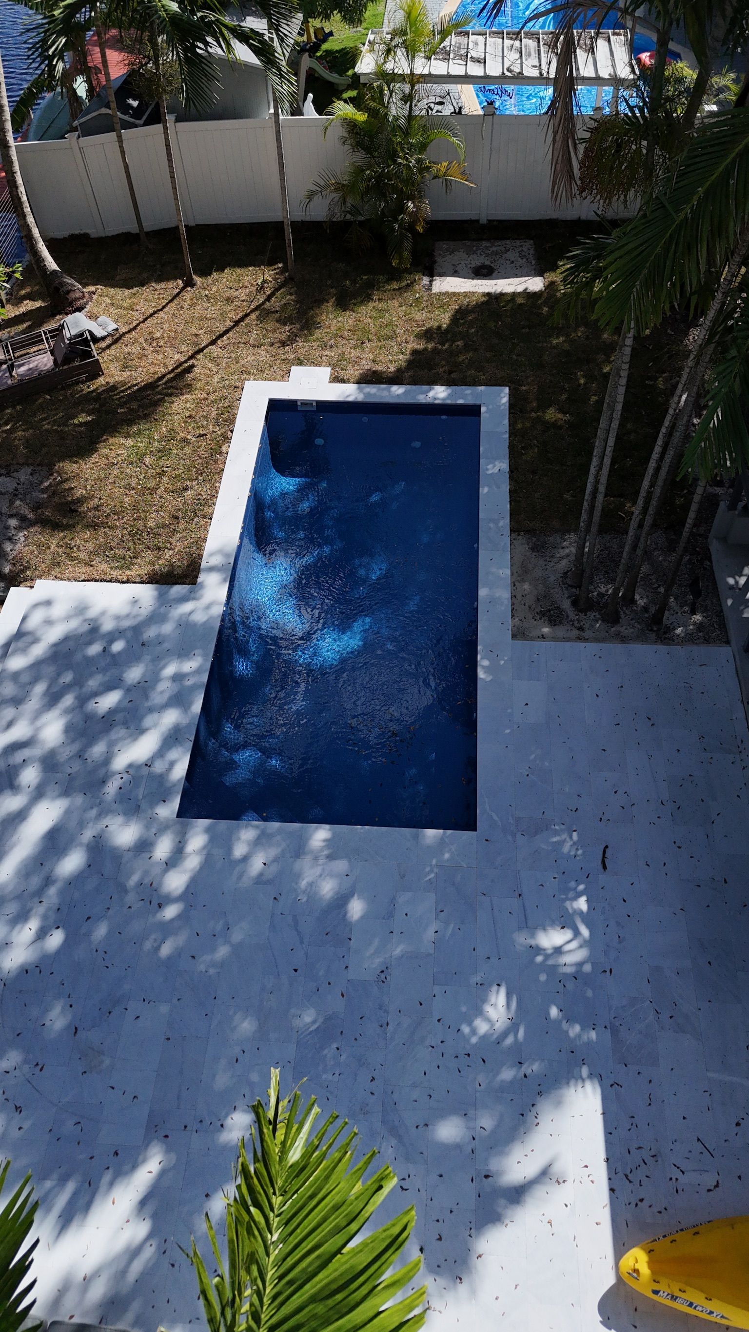 An aerial view of a swimming pool in a backyard surrounded by trees.