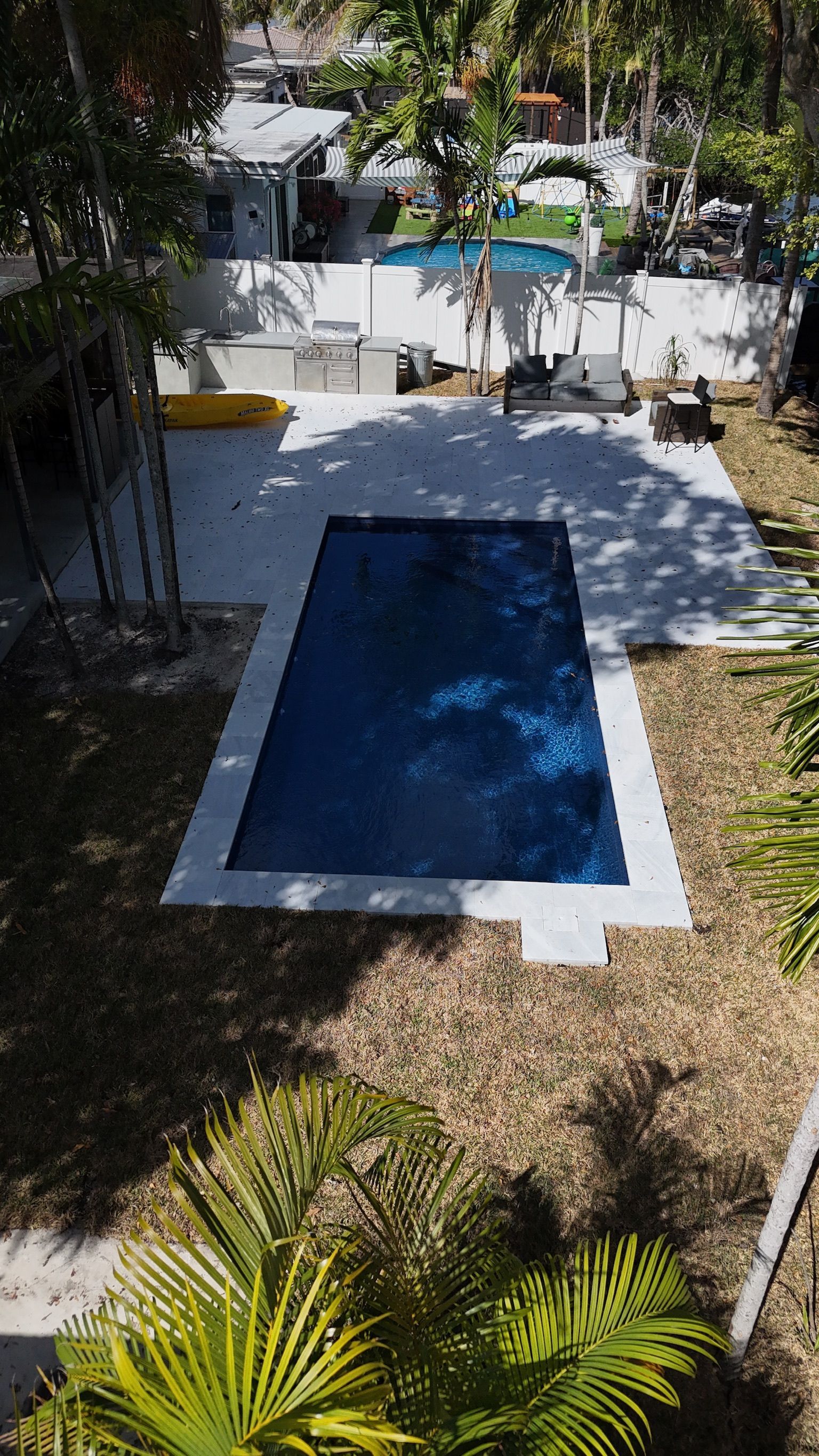 An aerial view of a large swimming pool in a backyard surrounded by trees.