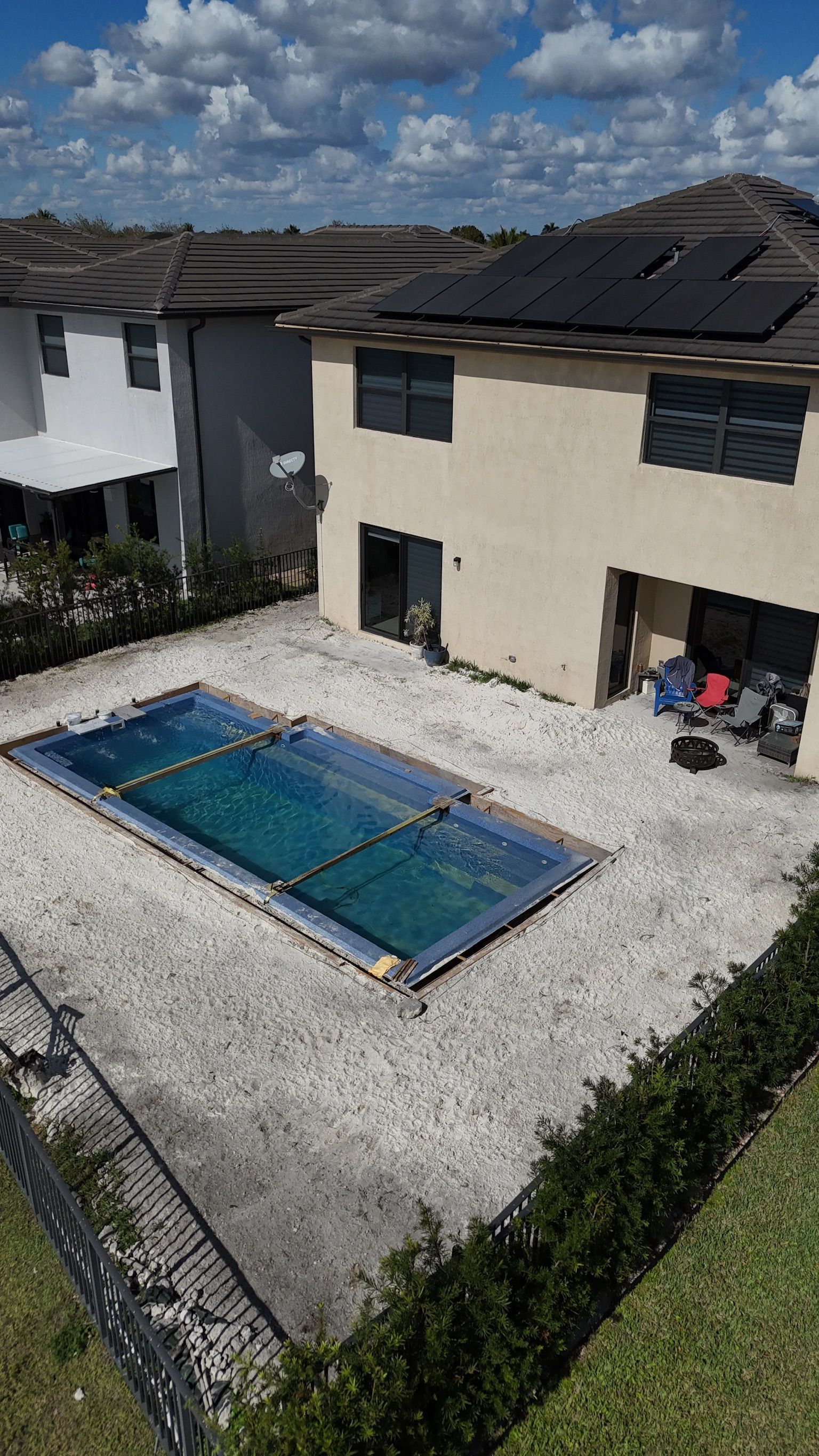 An aerial view of a swimming pool in the backyard of a house.