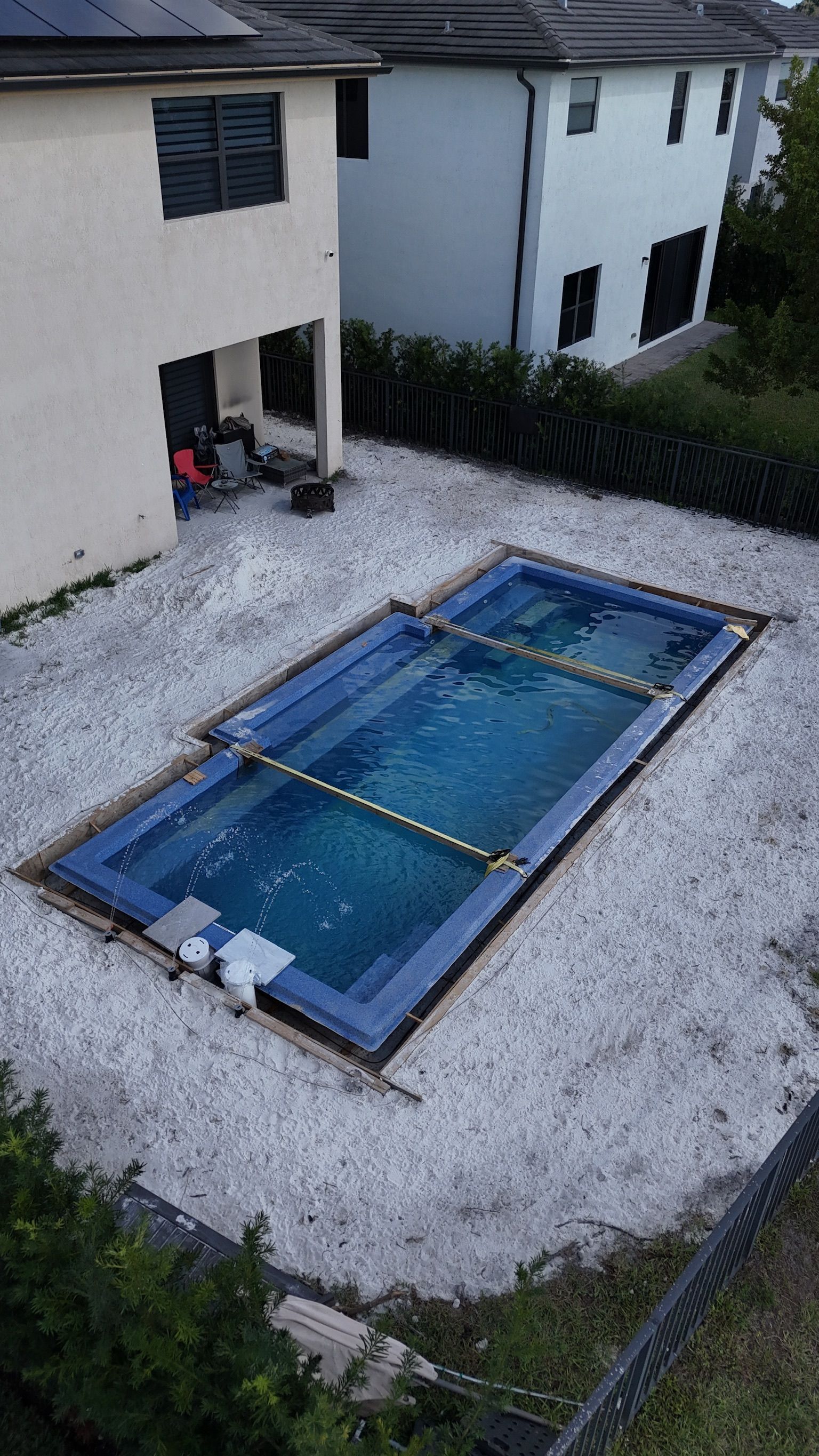 A large swimming pool is being built in the backyard of a house.
