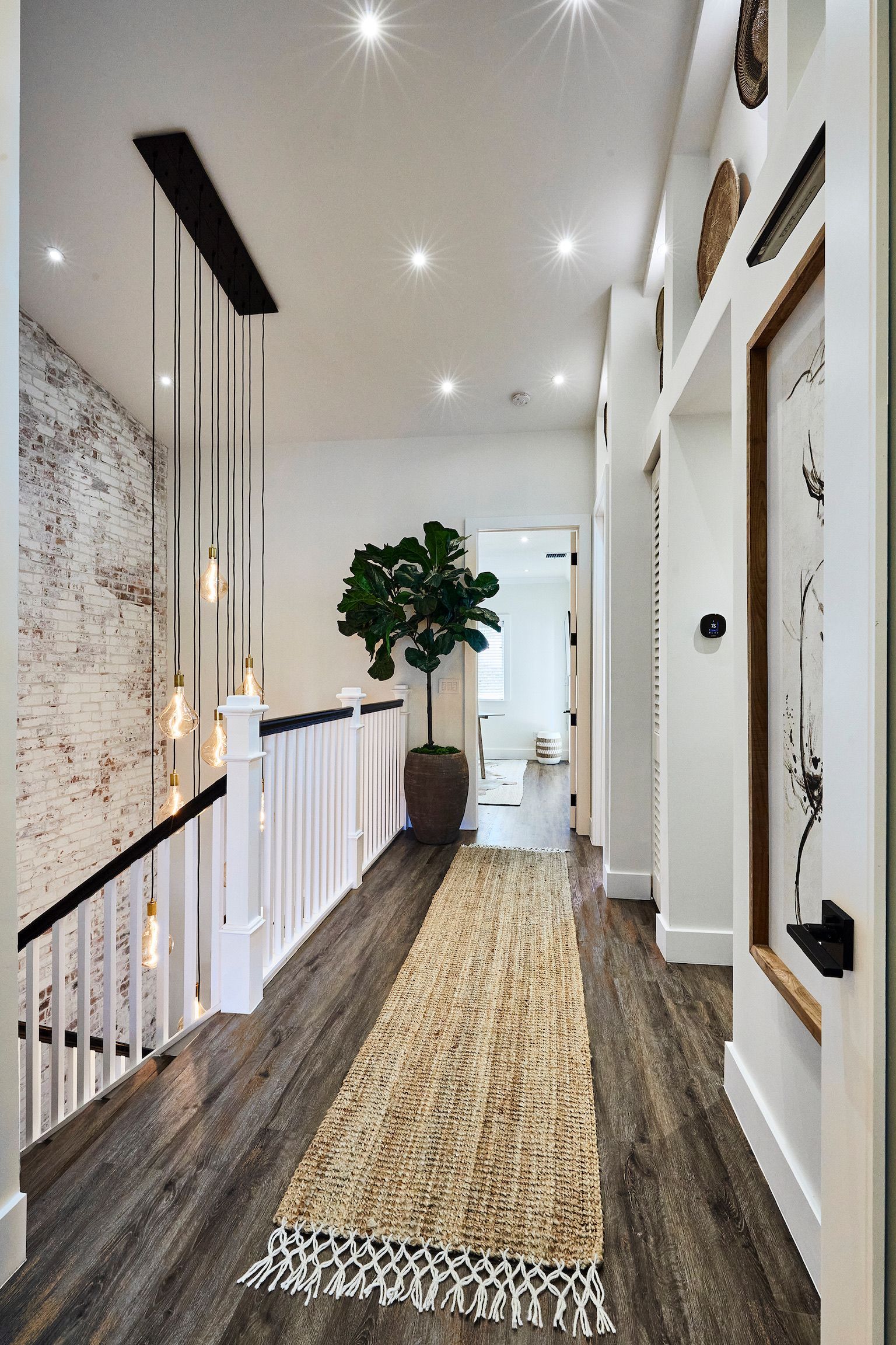 A hallway with a rug on the floor and a plant in the middle.