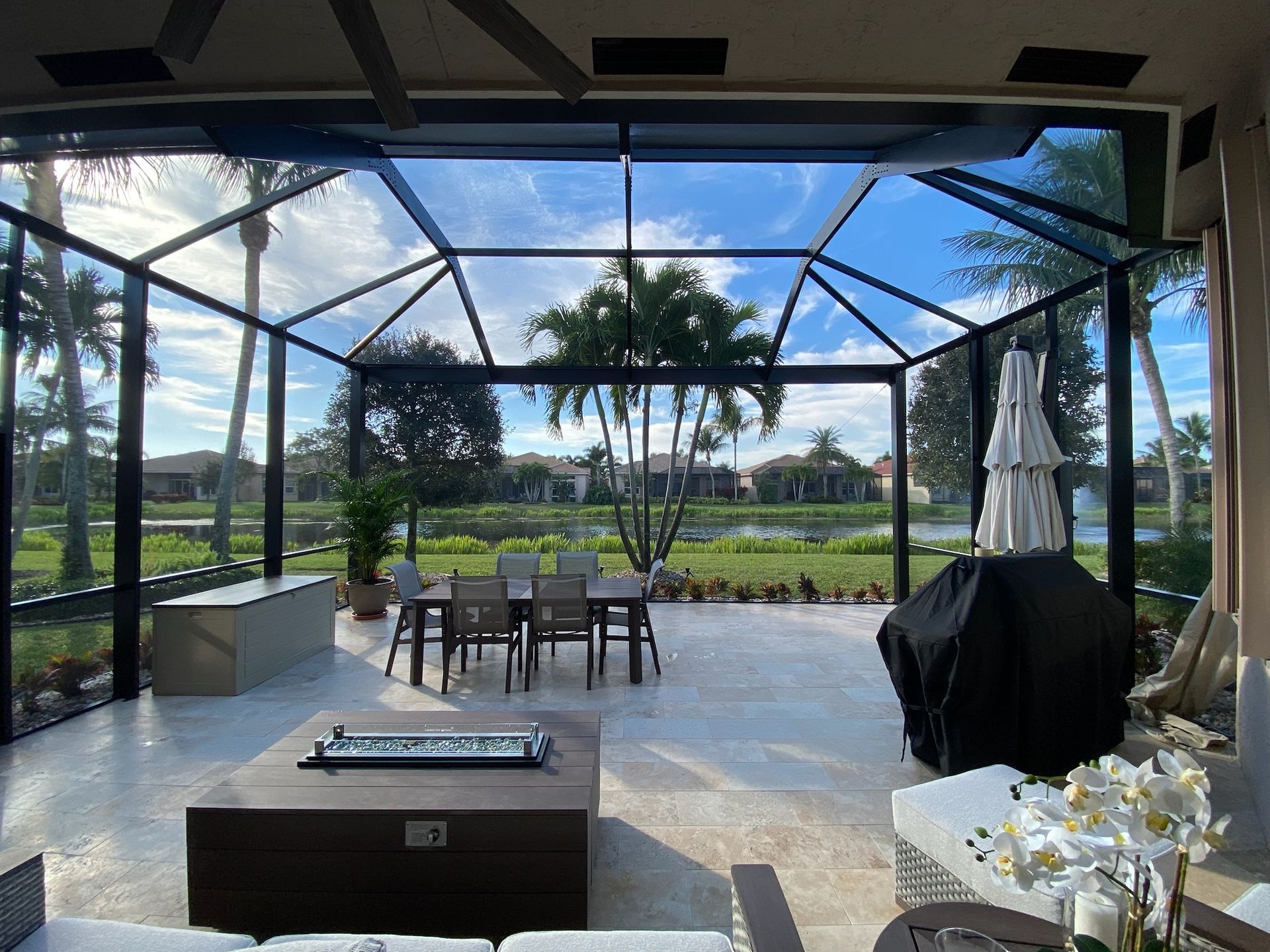 A screened in patio with a table and chairs and a fire pit.