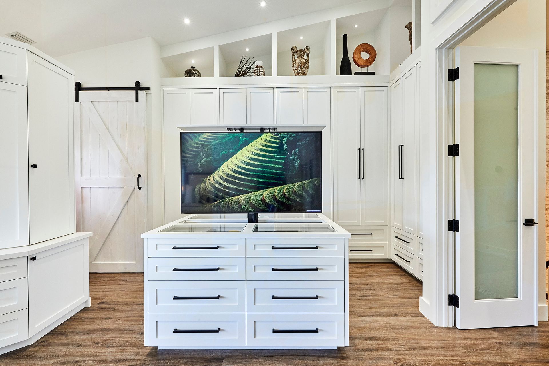 A living room with white cabinets and a flat screen tv on the wall.