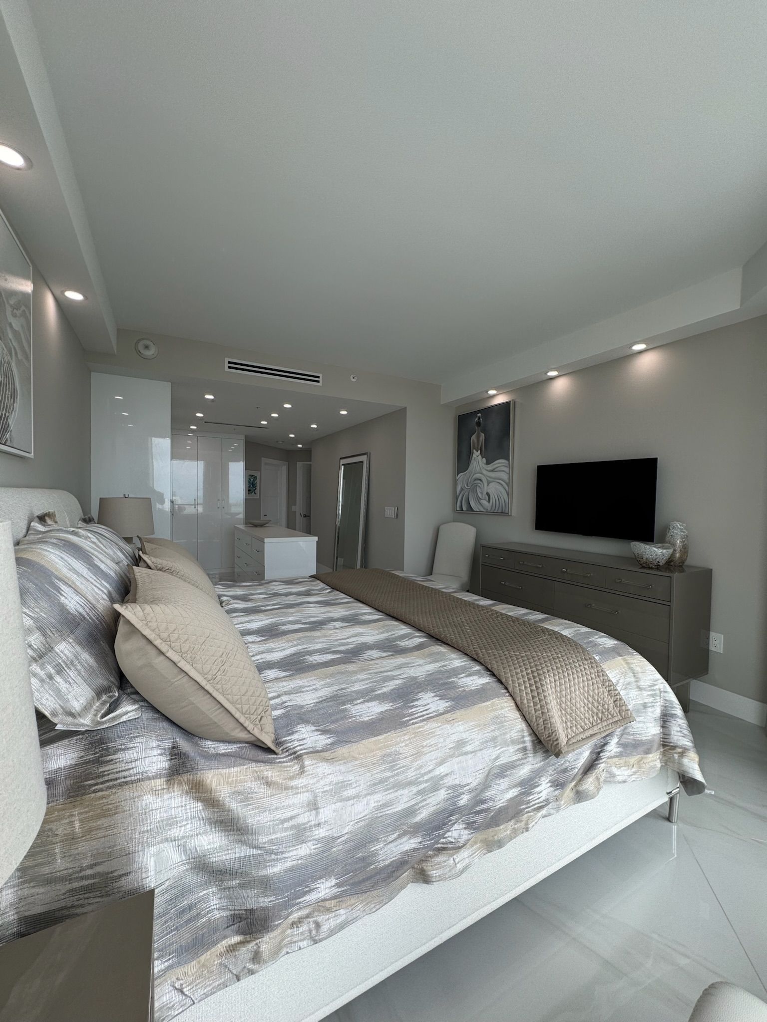 A bedroom with a large bed and a flat screen tv.
