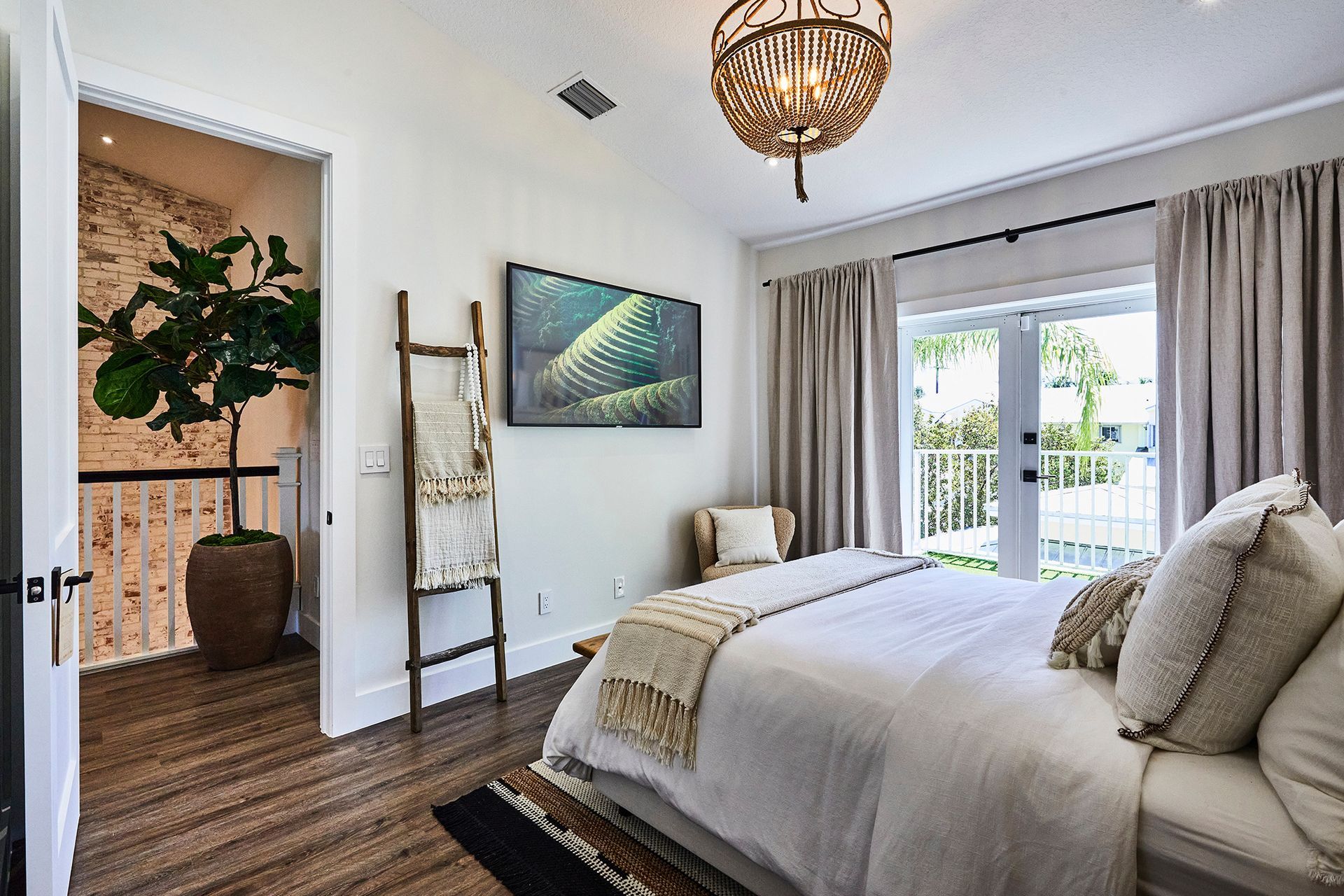 A bedroom with a large bed , a chair , a ladder and a television.