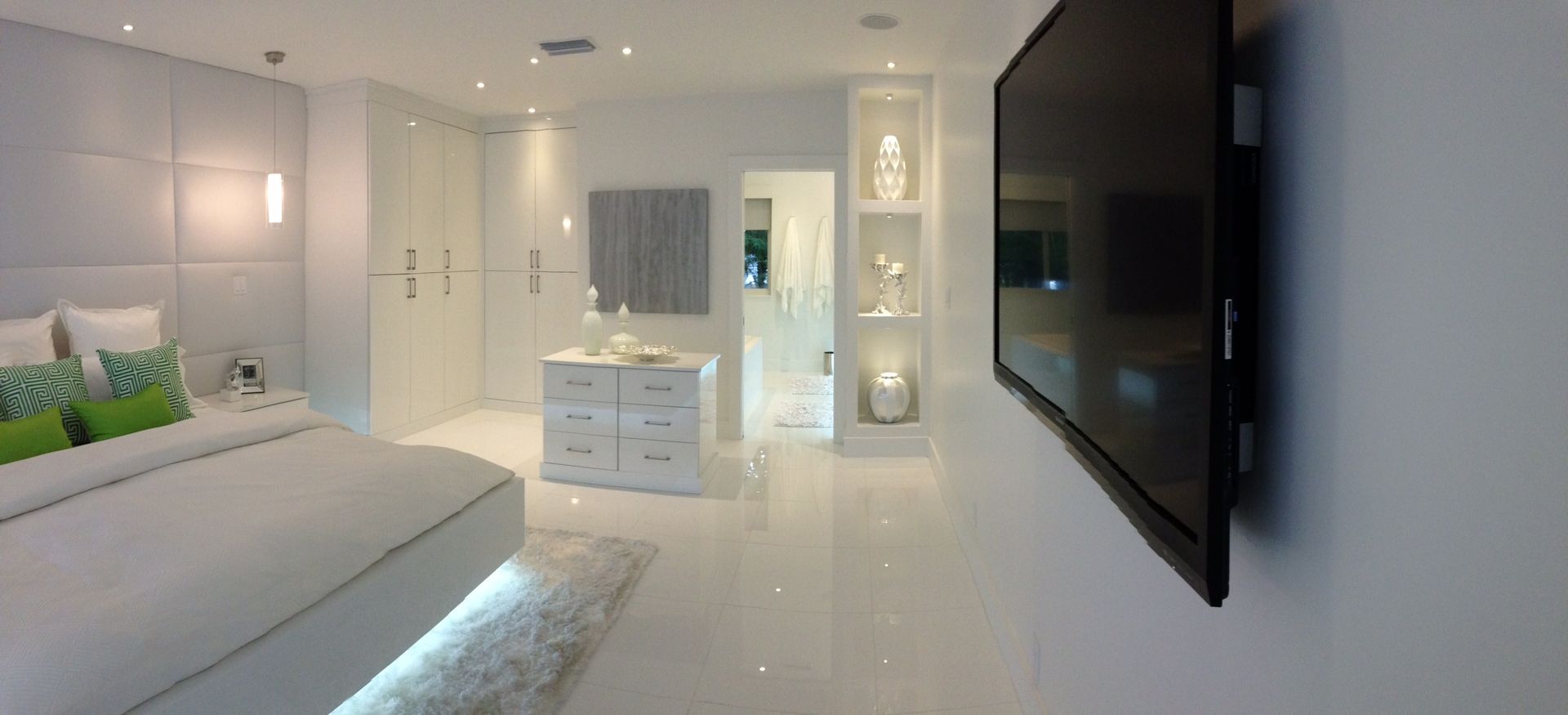 A bedroom with a large flat screen tv mounted on the wall.