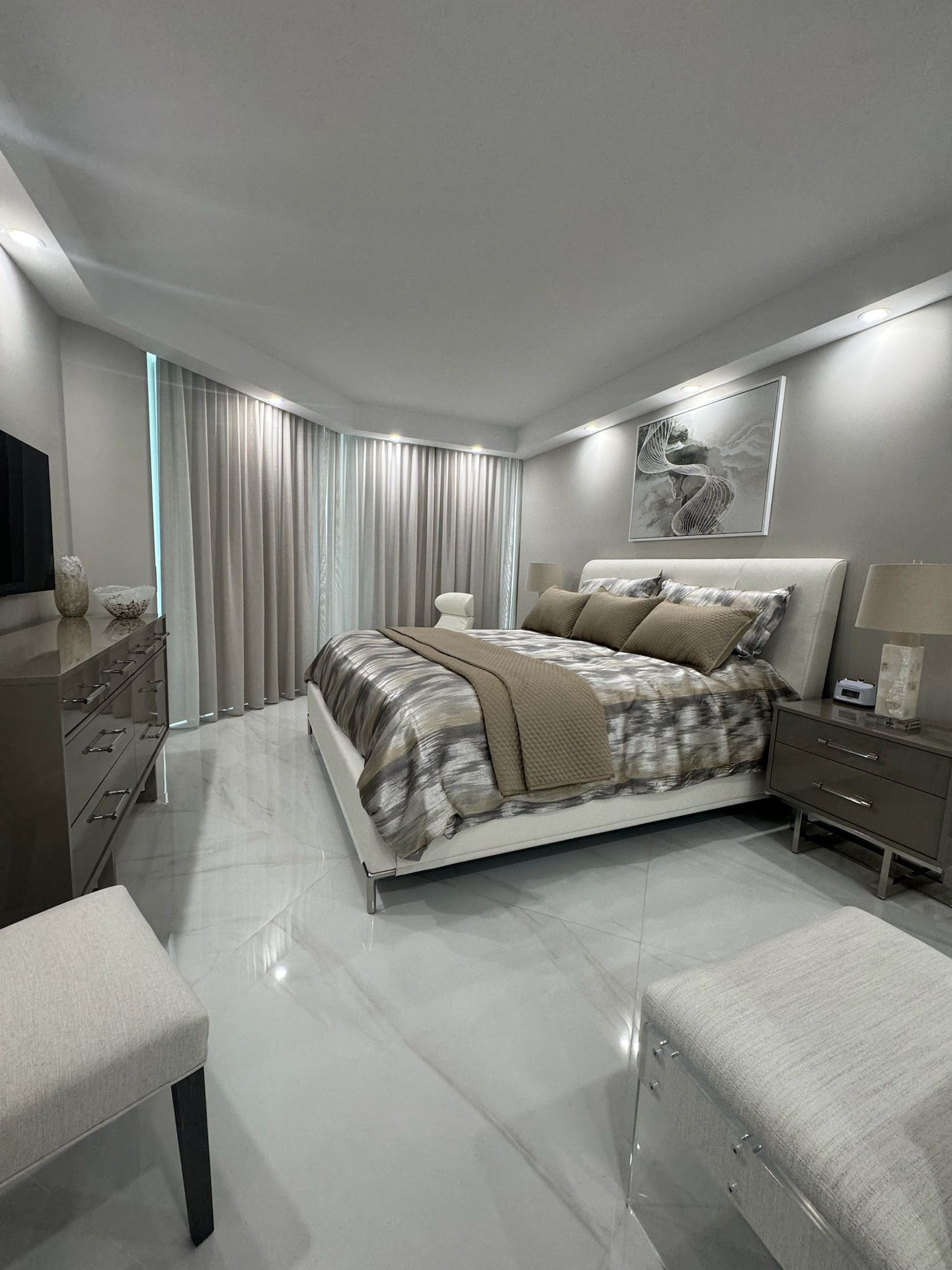 A bedroom with a large bed , dresser , nightstand , chair and television.