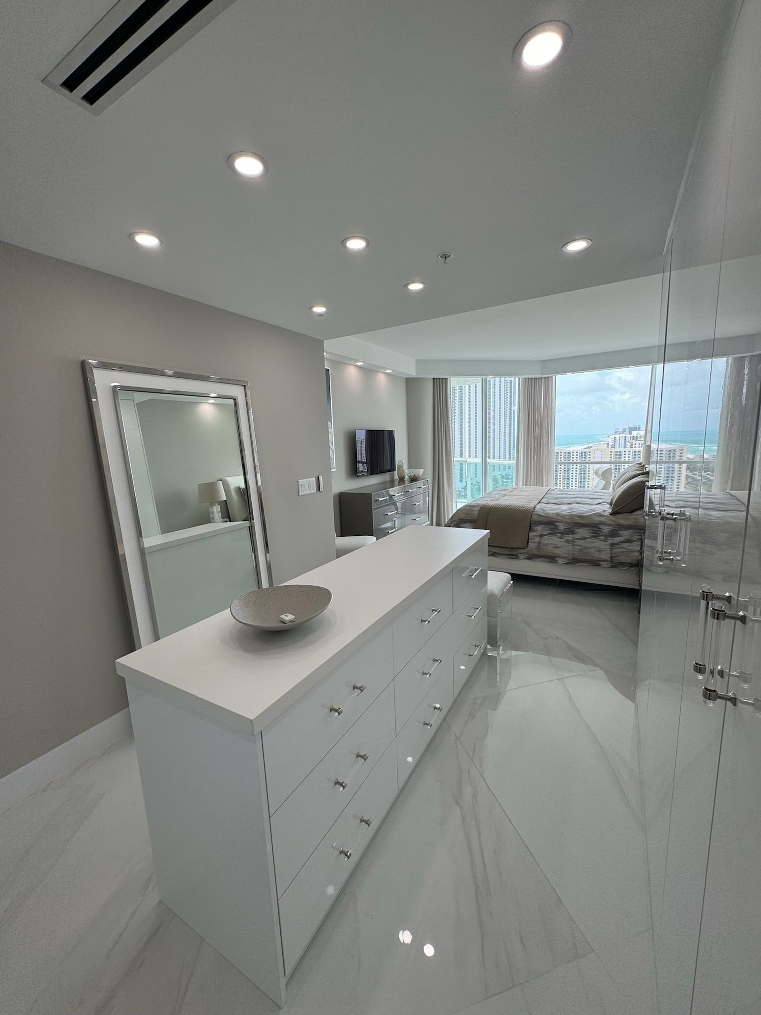 A bedroom with a large dresser and a large mirror.