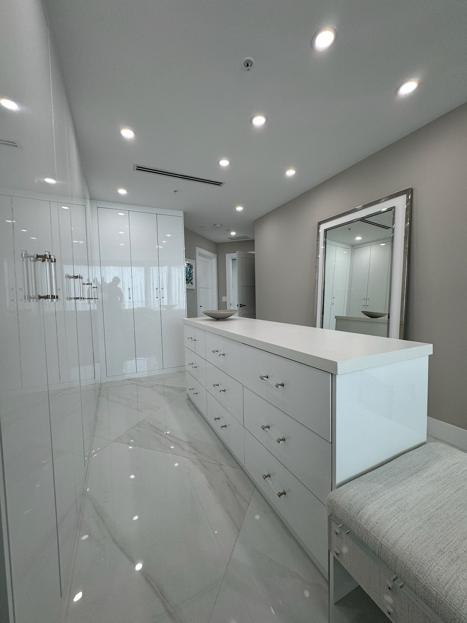 A large walk in closet with a large island and a mirror.