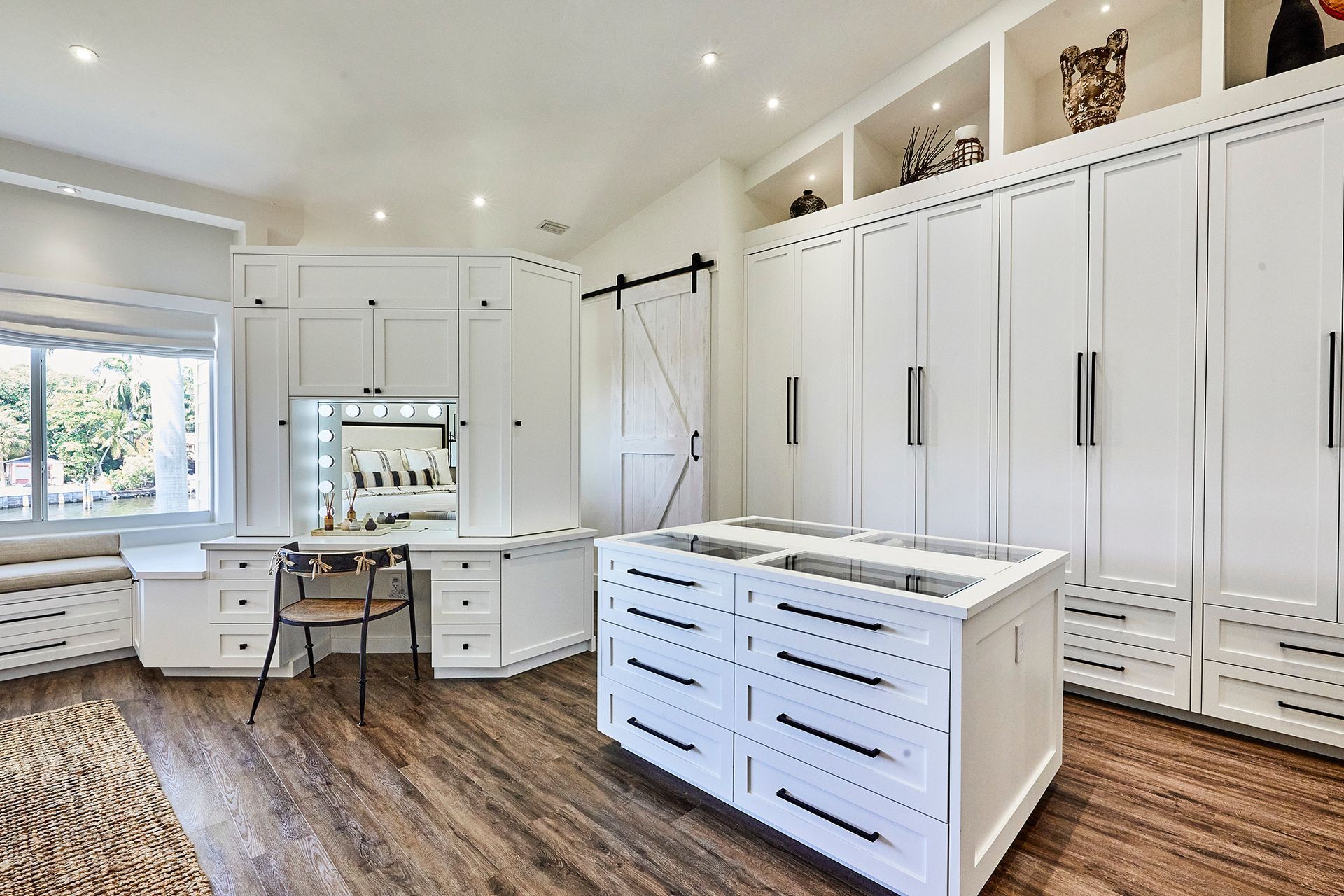 A large walk in closet with lots of white cabinets and drawers