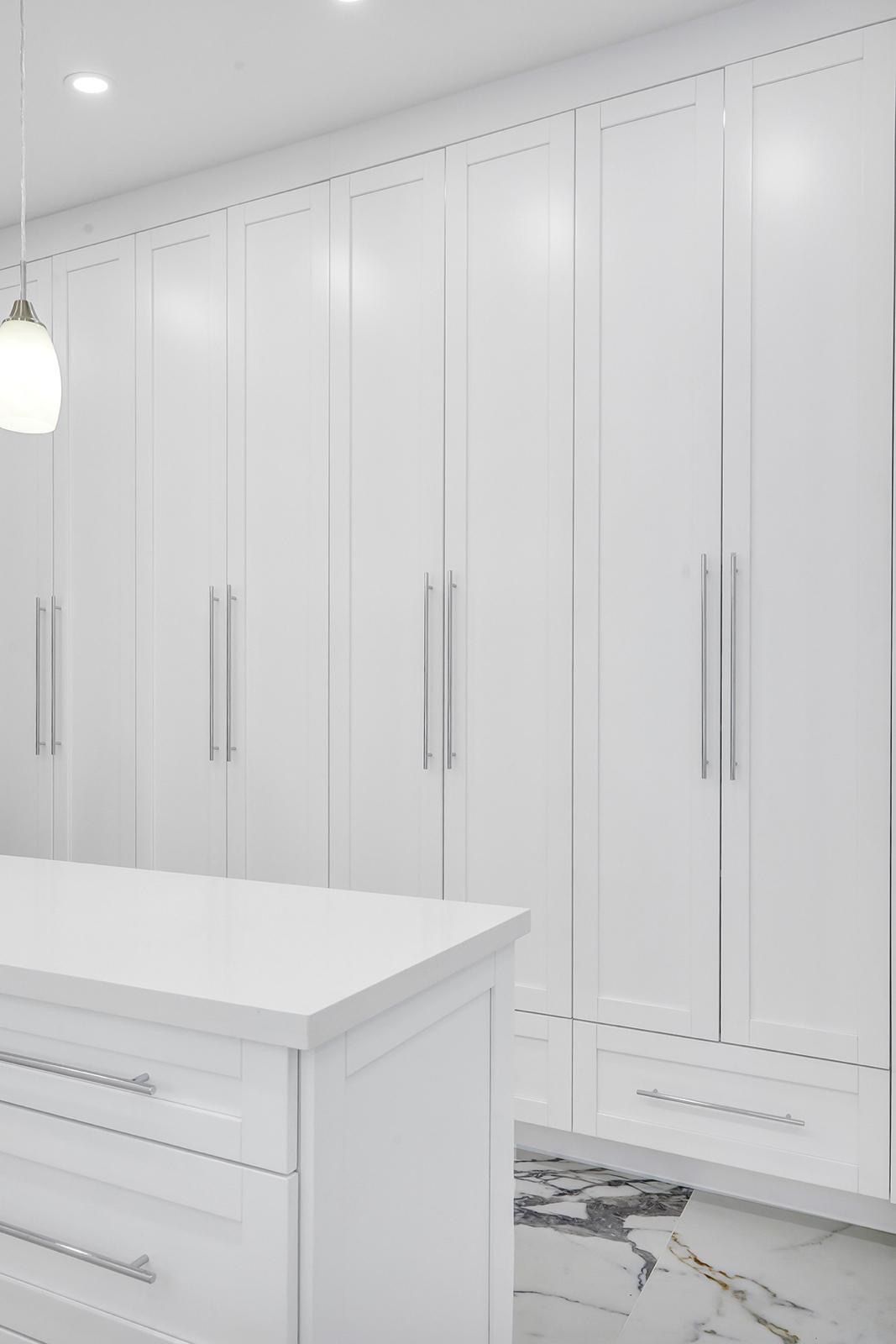 A kitchen with white cabinets and a white island.
