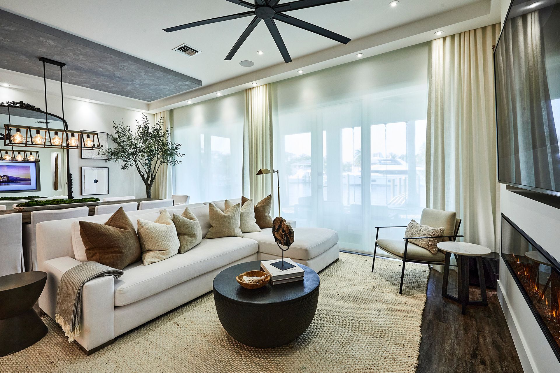 A living room with a couch , table , chairs and a ceiling fan.