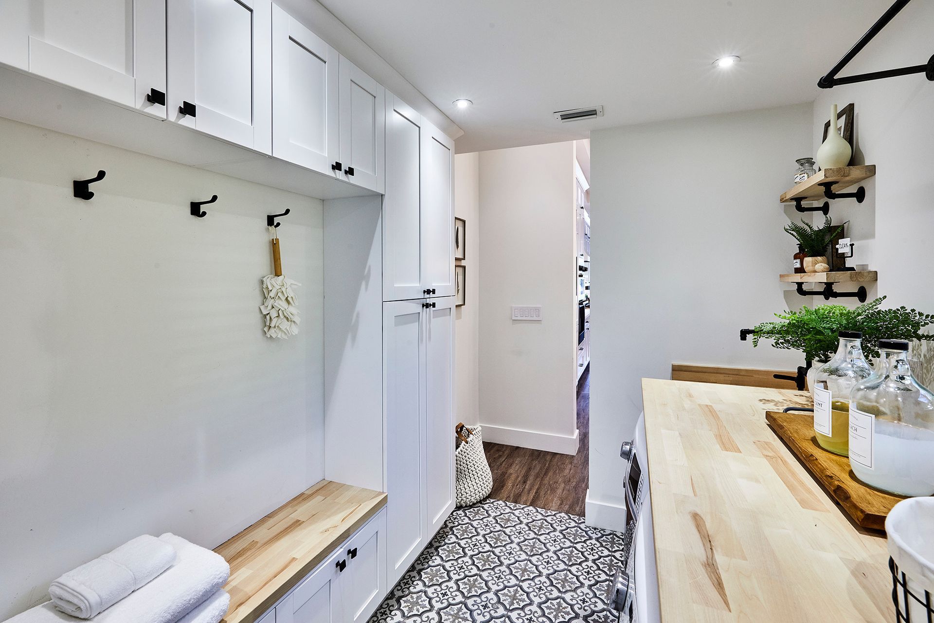 A laundry room with white cabinets and a wooden counter top.