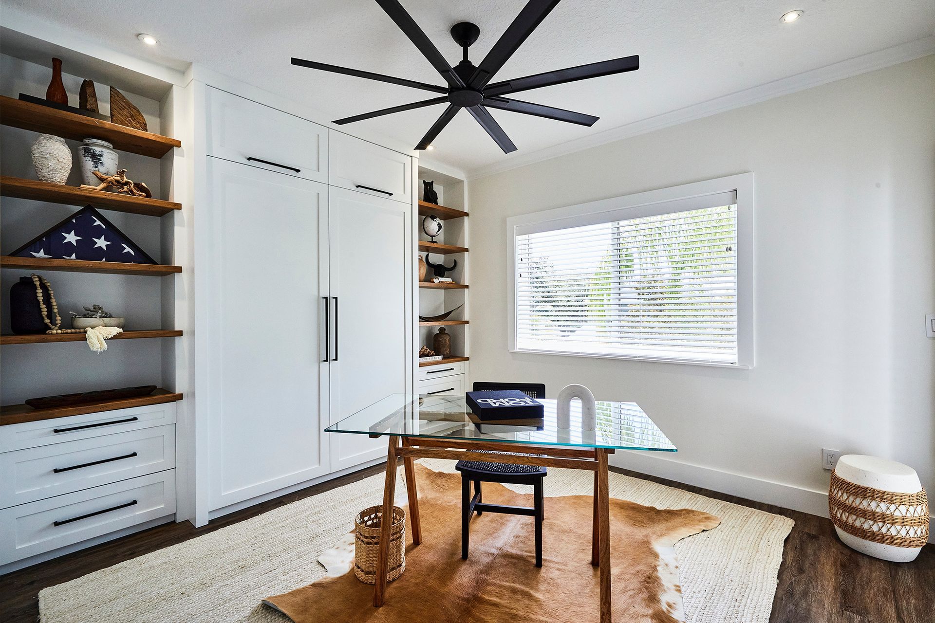 A home office with a desk and a ceiling fan.