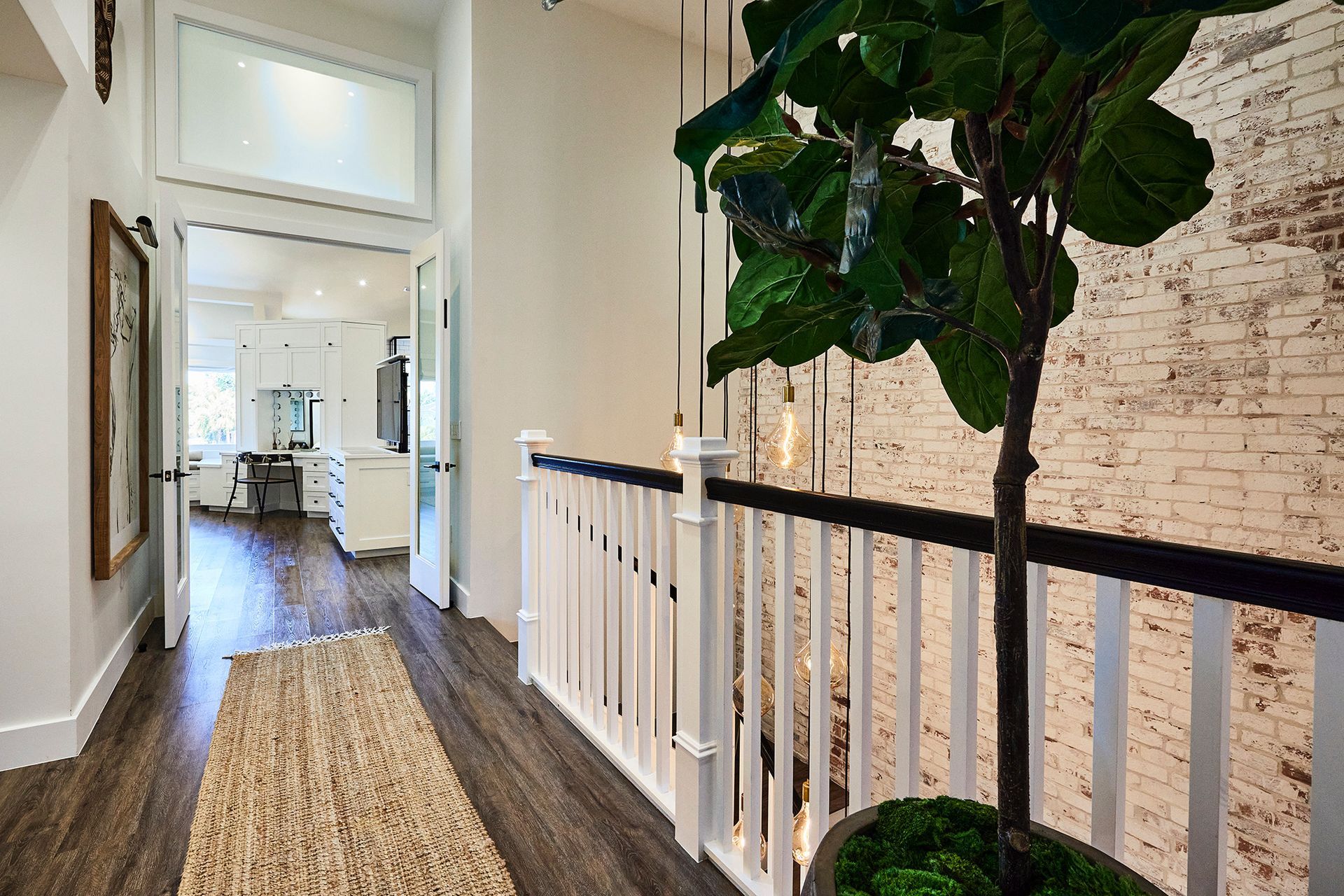 A hallway with a white railing and a plant in a pot.