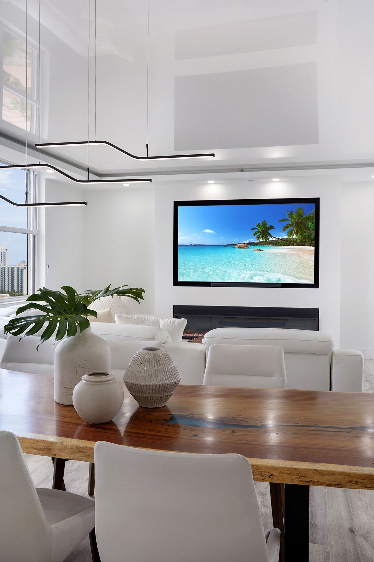 A living room with a dining table and chairs and a flat screen tv on the wall.