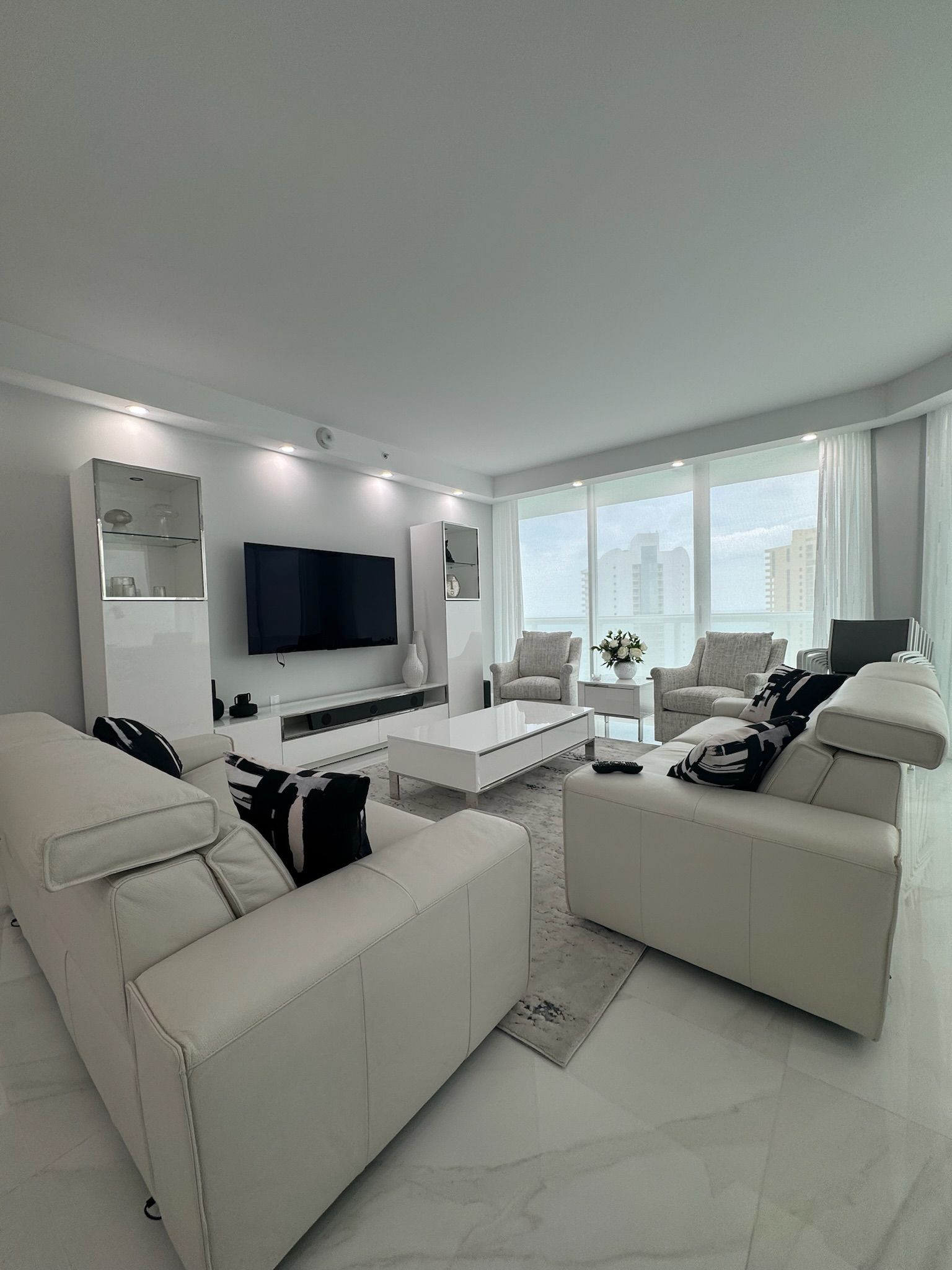 A living room with white furniture and a flat screen tv.