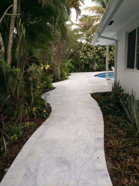A walkway leading to a house with a pool in the background