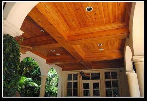 A porch with a wooden ceiling and a ceiling fan