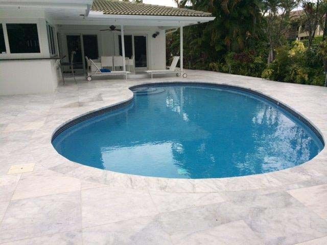 A large swimming pool with a white house in the background