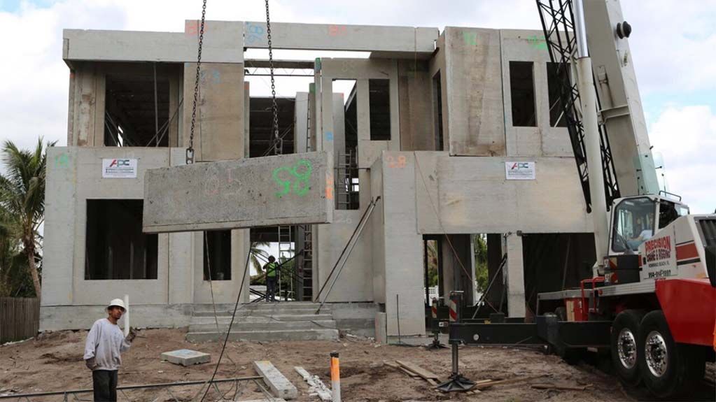 A man stands in front of a building under construction