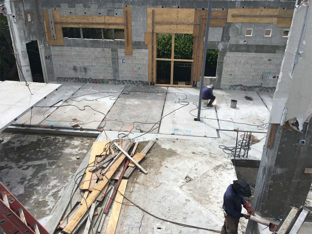 A man is working on the floor of a building under construction.