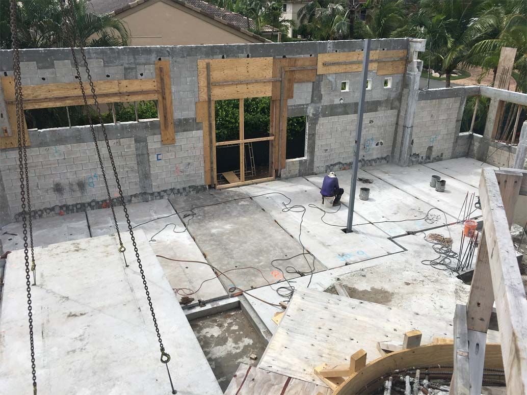 A man is sitting on a chair in front of a building under construction.