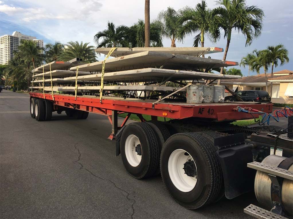 A semi truck is carrying a stack of stainless steel pipes