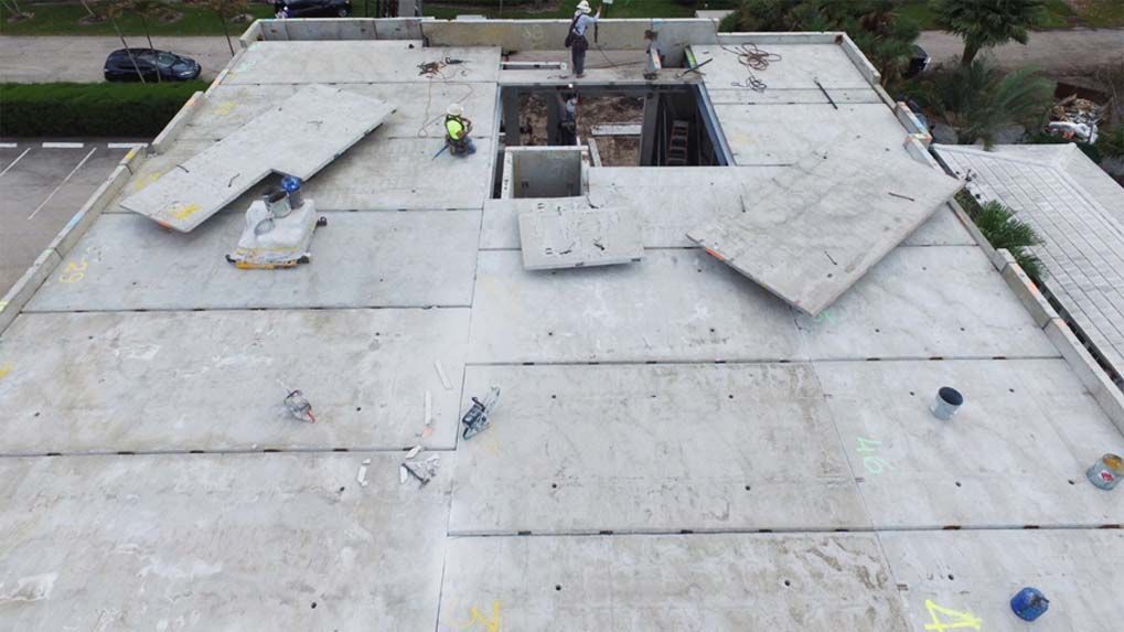 An aerial view of a building under construction with workers on the roof.