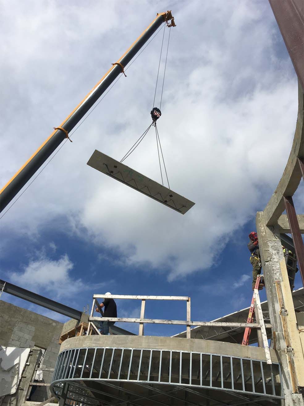A crane is lifting a piece of concrete into the air.