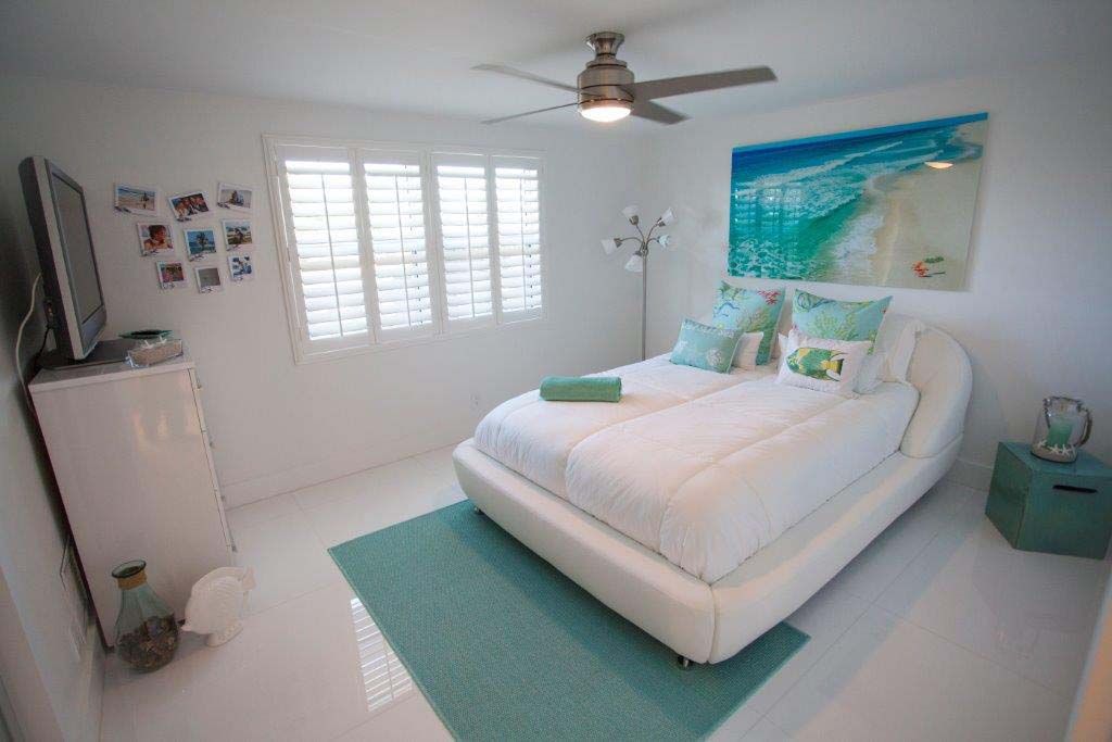 A bedroom with a white bed and a blue rug.