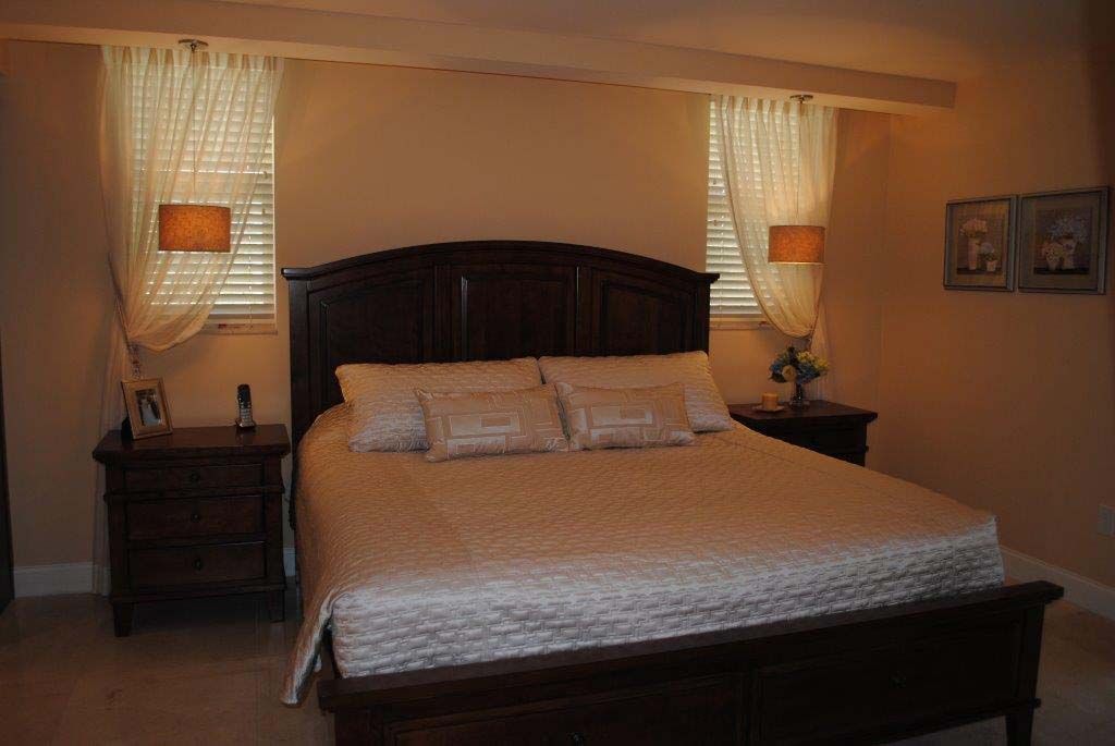 A bedroom with a king size bed , two nightstands , and two windows.