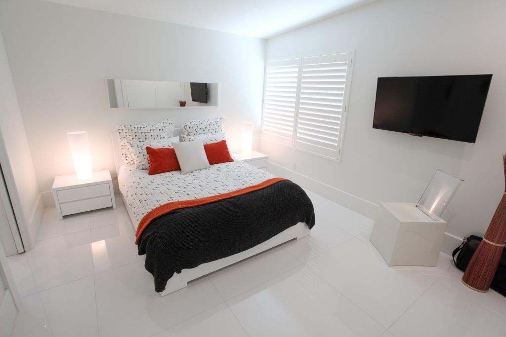 A bedroom with a king size bed and a flat screen tv on the wall.