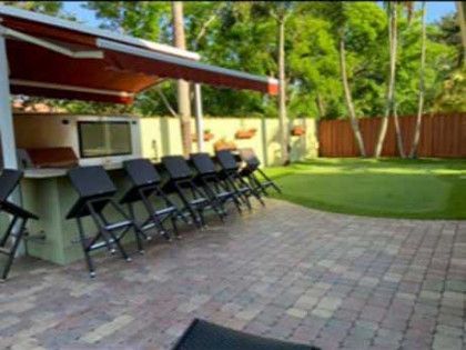 A patio with a bar and stools under an awning