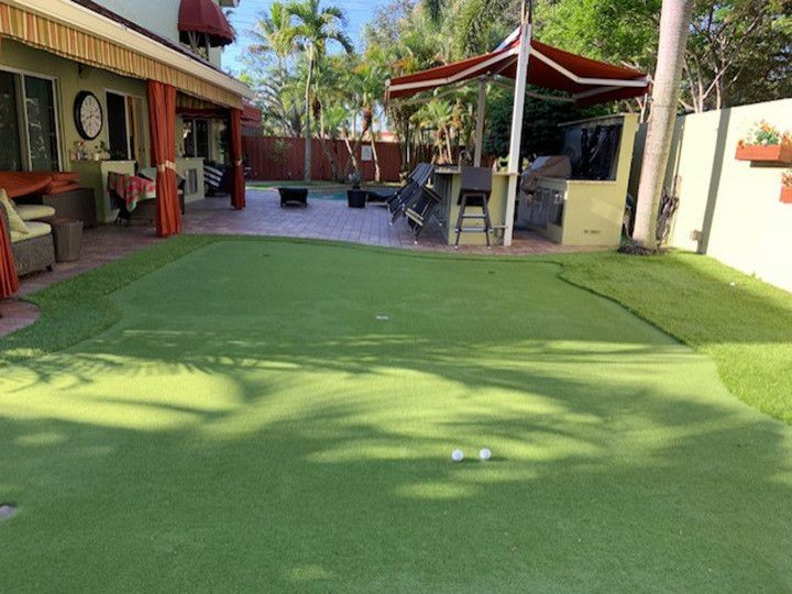 There is a putting green in the backyard of a house.