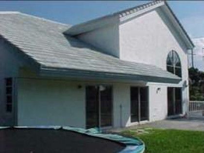 A large white house with a trampoline in front of it.