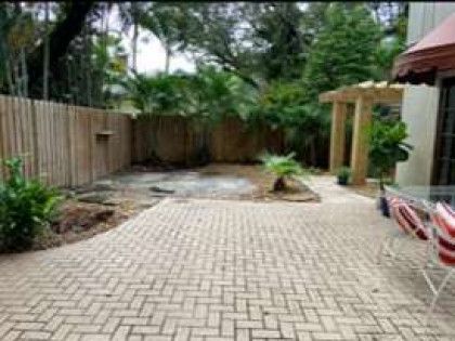 A brick patio with a wooden fence and a table and chairs in the backyard of a house.