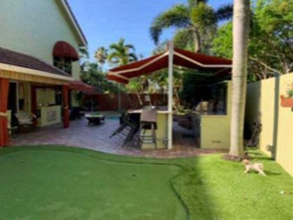 A dog is standing in the grass in front of a house.