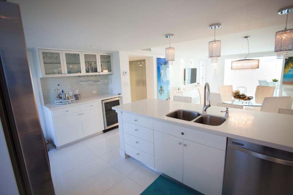 A kitchen with white cabinets , a sink , and a dishwasher.
