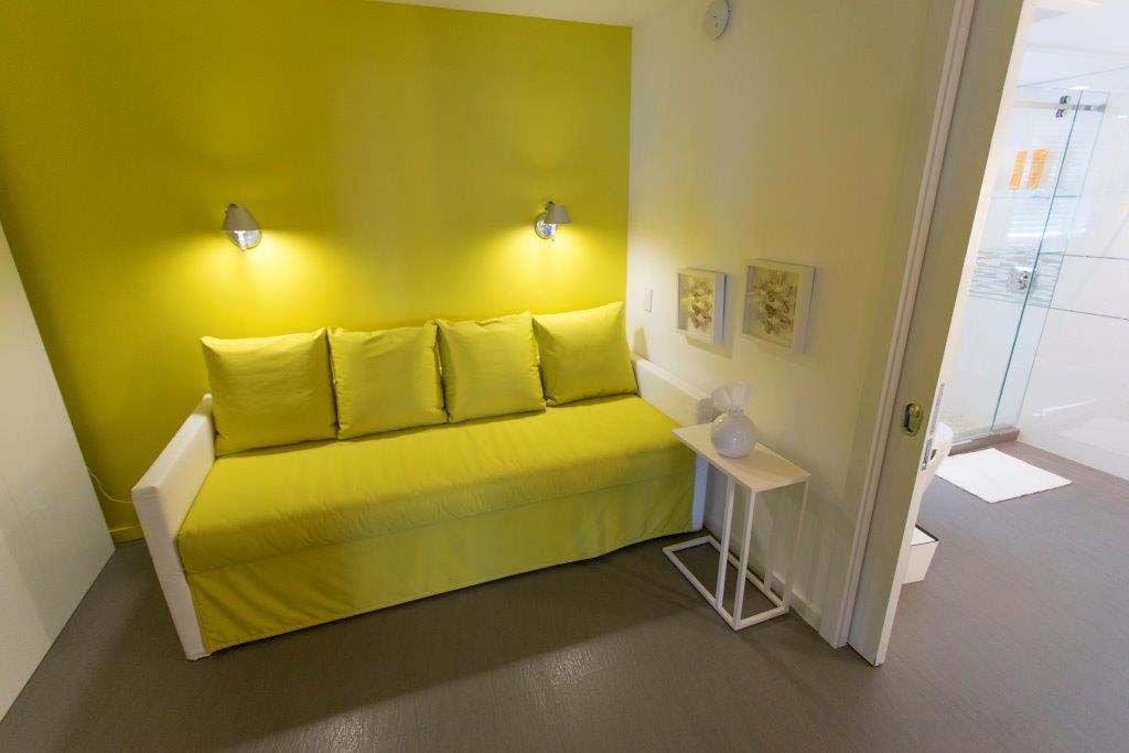 A living room with a yellow couch and a yellow wall.
