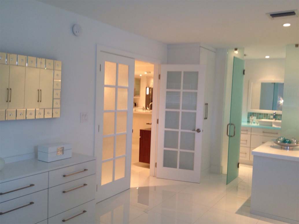A bathroom with white cabinets and french doors