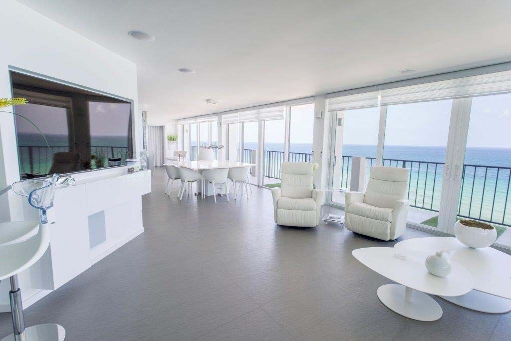 A living room with white furniture and a view of the ocean