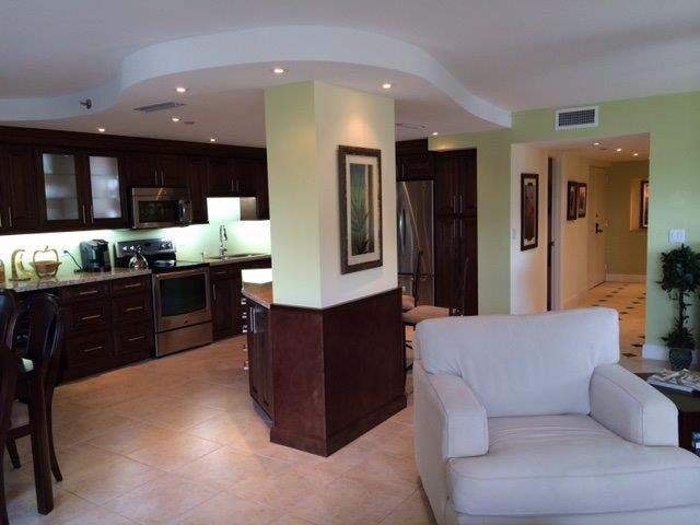 A living room with a white chair and a kitchen