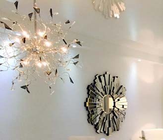 A bathroom with a chandelier and a mirror on the wall.