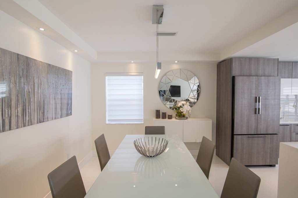 A dining room with a white table and brown chairs